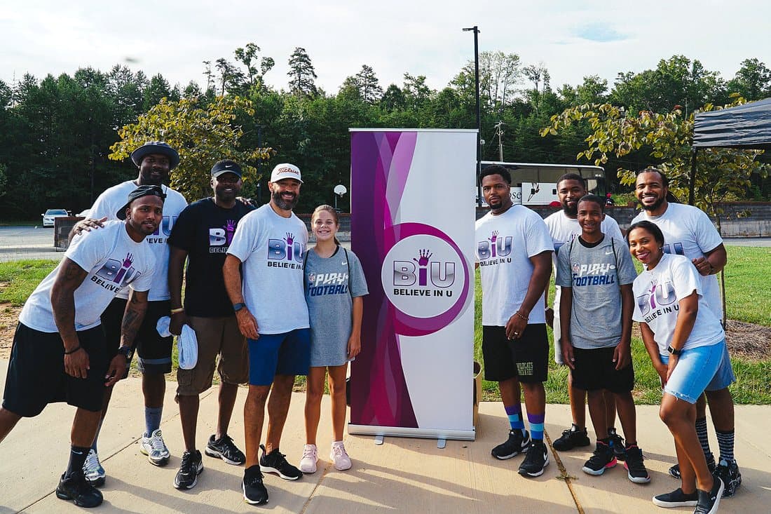 A large group of students and volunteers in Believe In U shirts posing outdoors