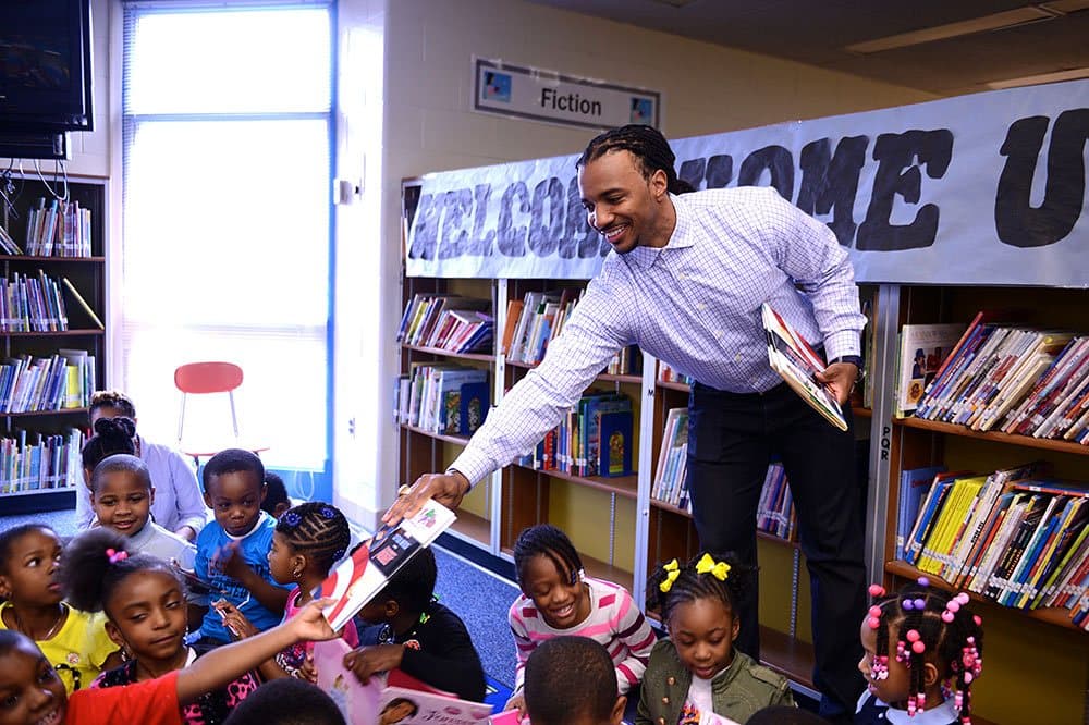 A volunteer handing books to children in a school library
