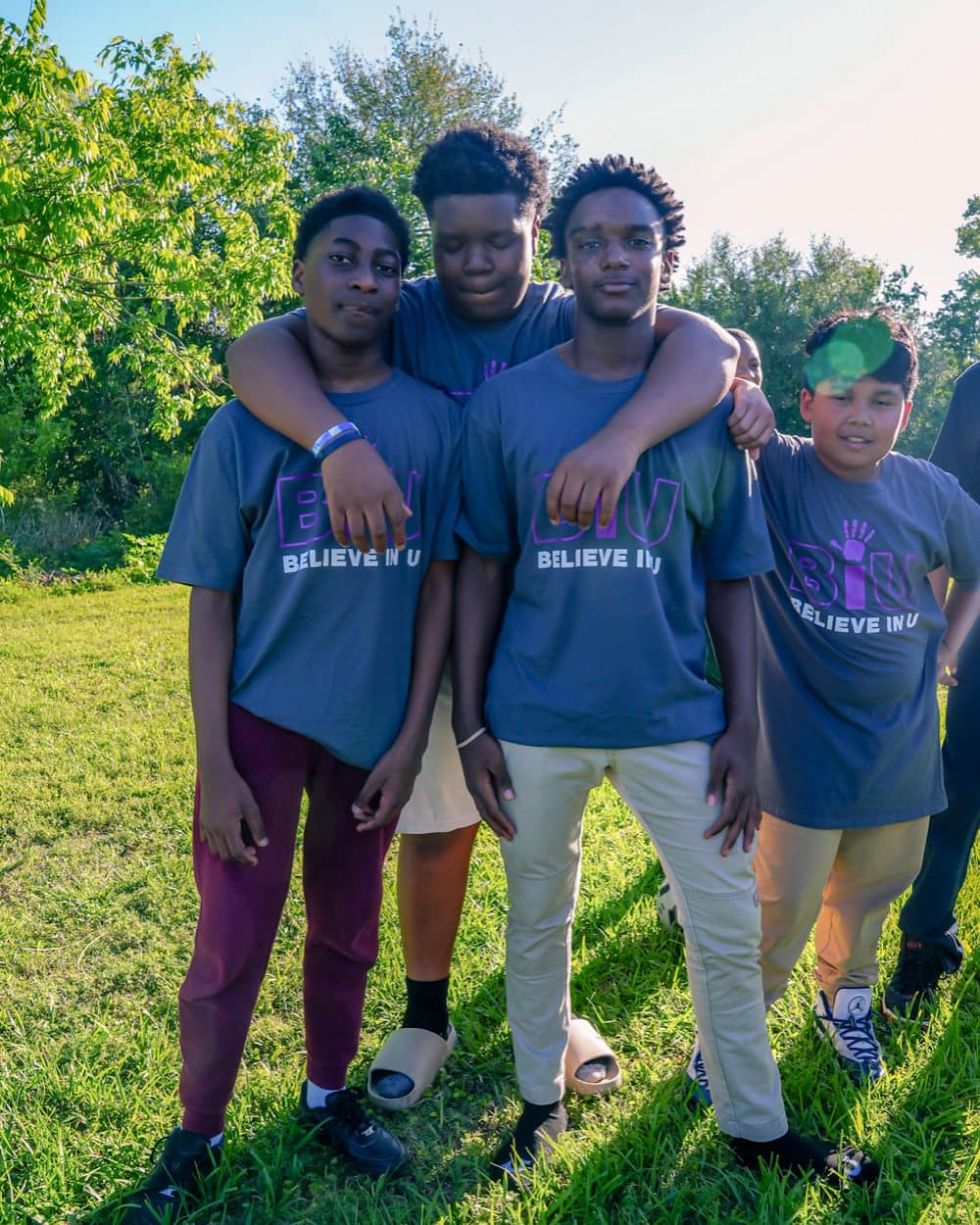 A mentor with his arm around a student, both in Believe In U shirts