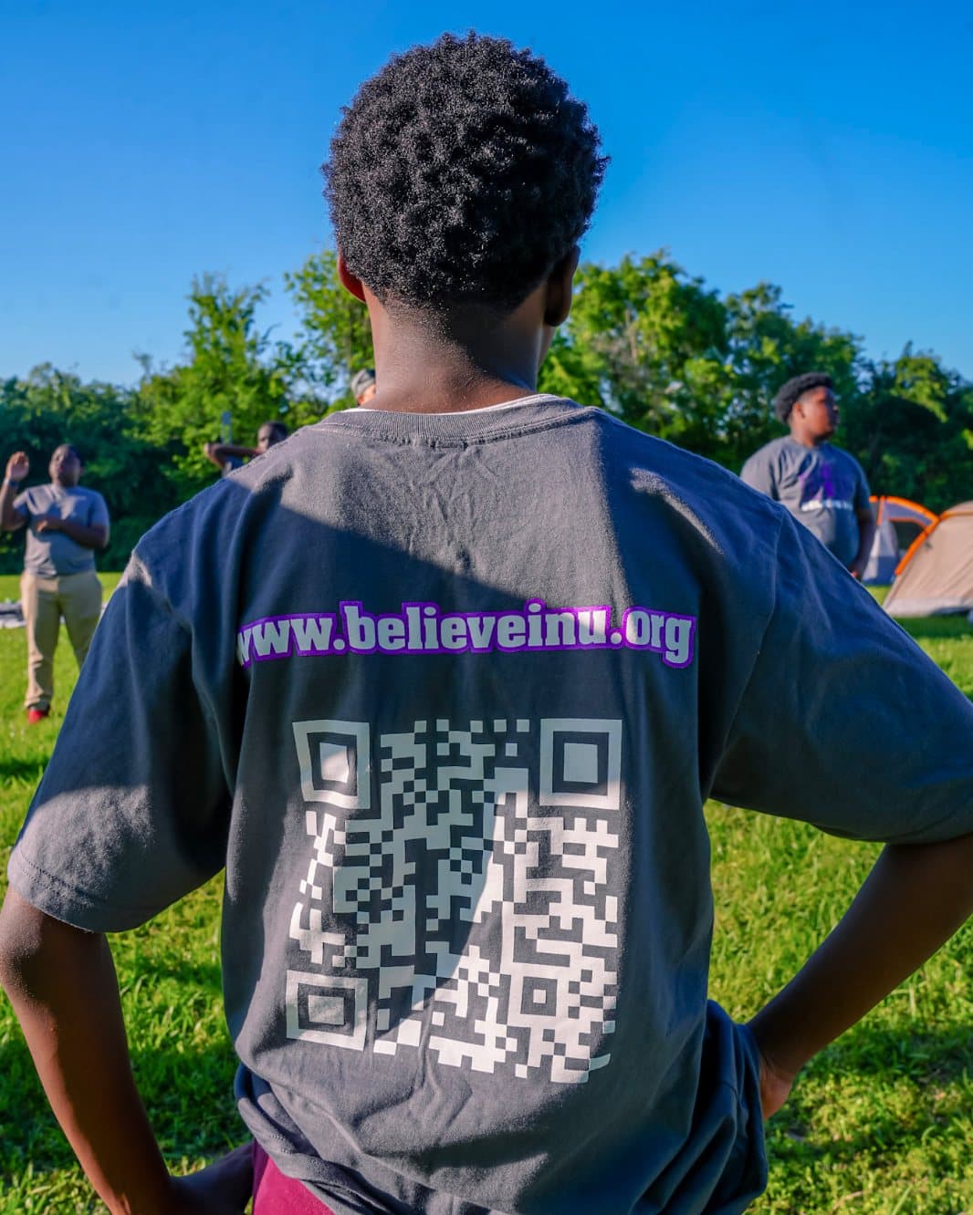 Three teenage boys in Believe In U shirts outdoors